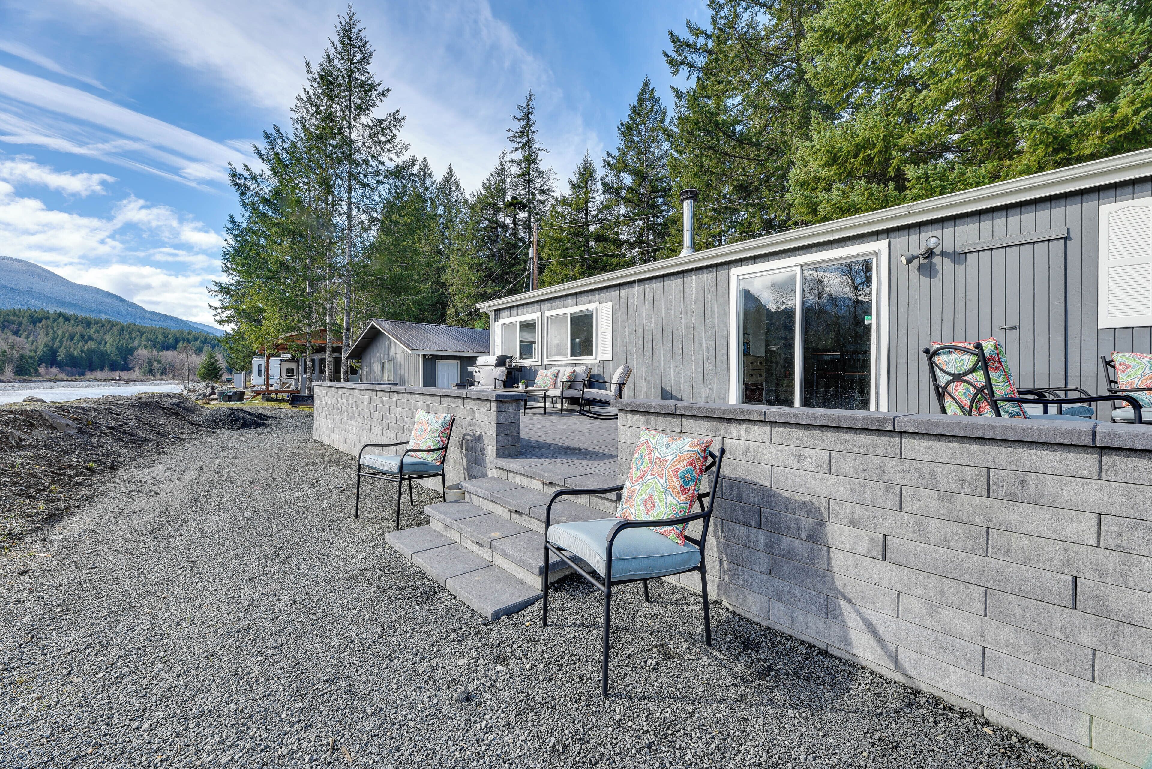 A cabin with a gravel patio, outdoor seating, and a view of a forested area.