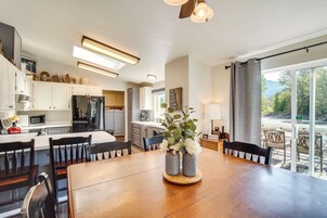 Una cocina moderna con armarios blancos, una mesa de comedor de madera y vistas al exterior a través de amplios ventanales.