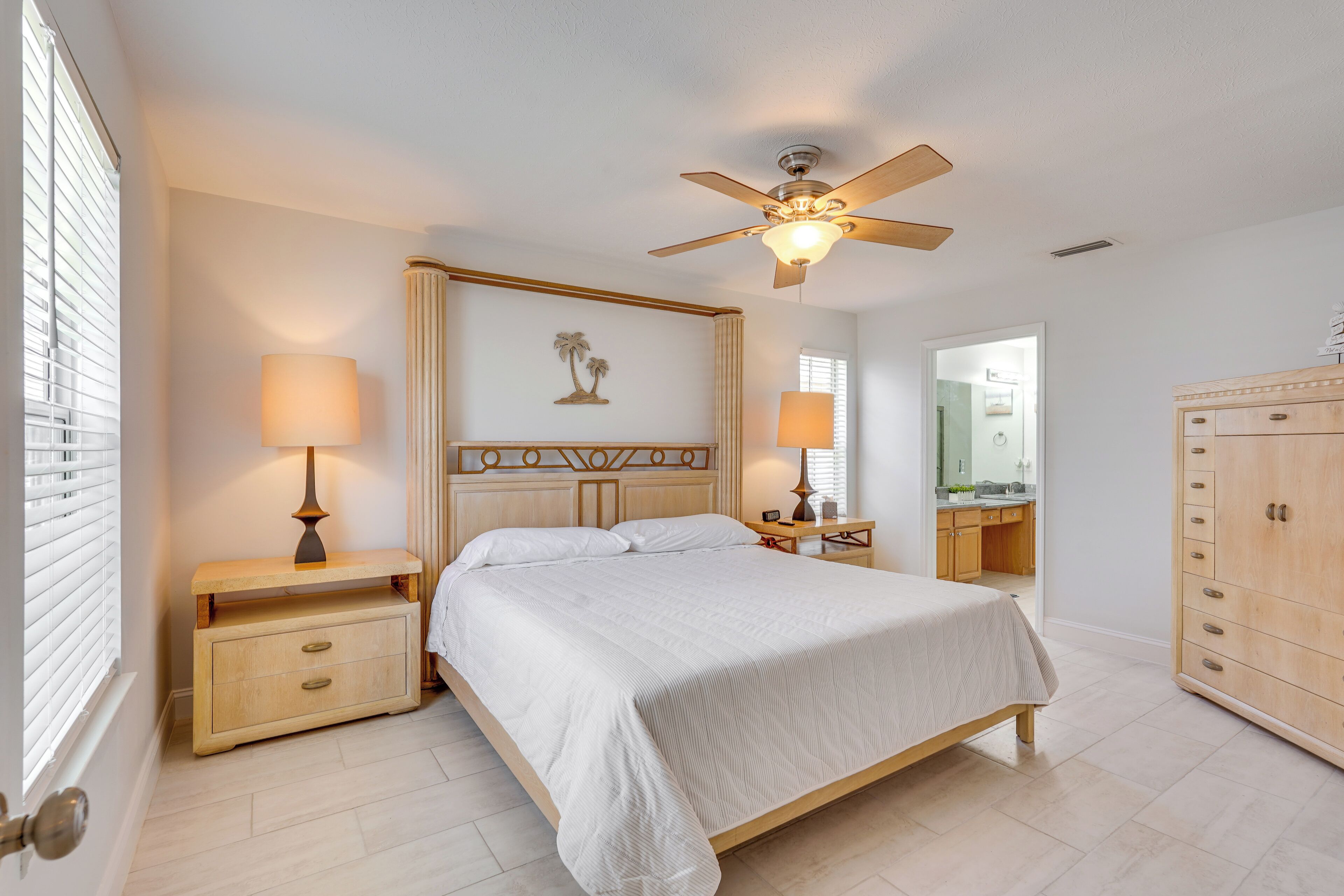 A bedroom with a bed, bedside tables, a ceiling fan, and a wardrobe.