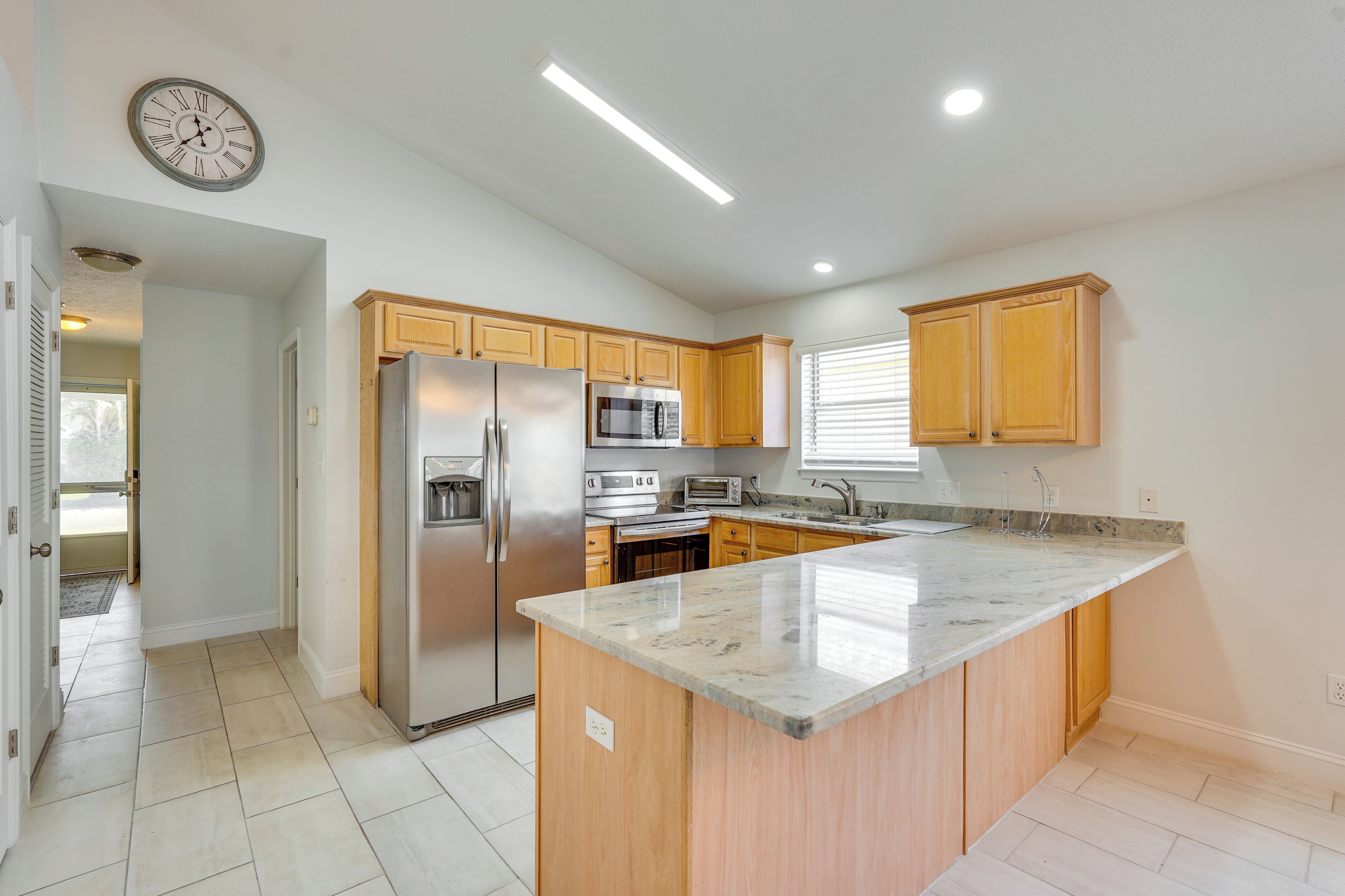 A modern kitchen with wooden cabinets, stainless steel appliances, and a marble countertop.