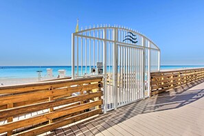 A wooden boardwalk leading to a beach with a white metal gate. - Panama City Beach Condo: Balcony w/ Ocean Views! (Panama City Beach)