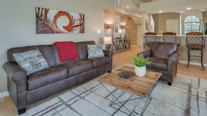 A spacious living area with a brown leather sofa, a wooden coffee table, and a large abstract painting on the wall. - Branson Vacation Rental w/ Pools & Hot Tub! (Branson)