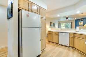 A modern kitchen with wooden cabinets, a white refrigerator, and a dishwasher.
