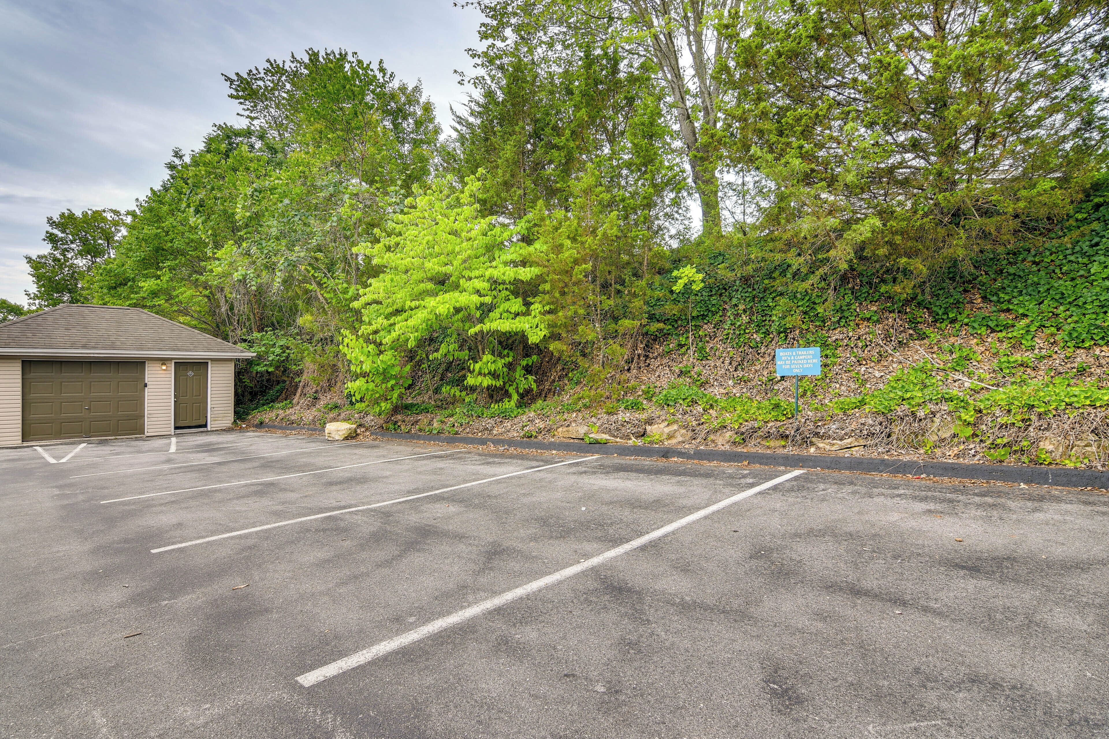 A parking lot with marked spaces, a building with a garage door, and a sign on a hill.