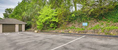 A parking lot with marked spaces, a building with a garage door, and a sign on a hill.