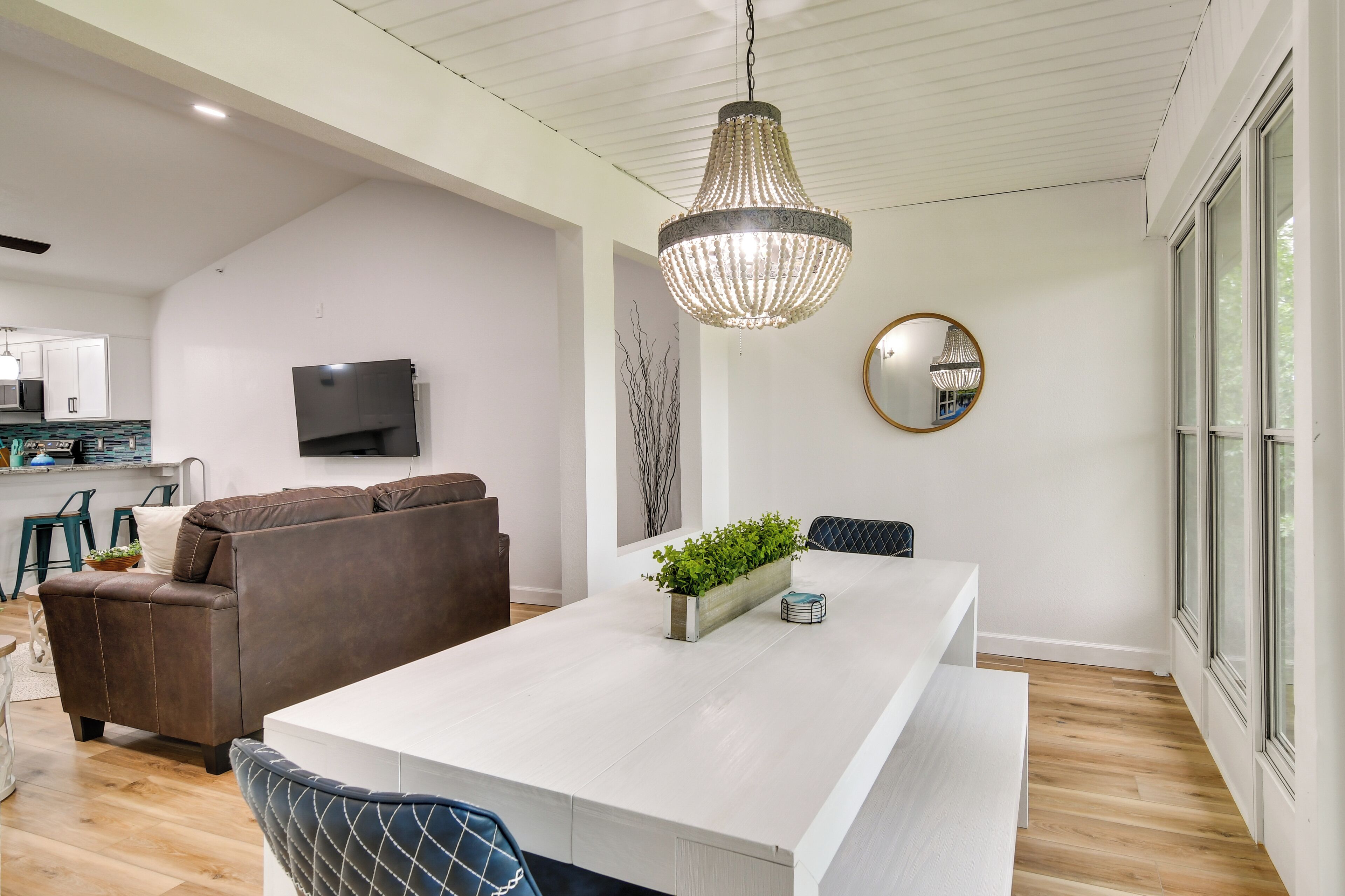 Een moderne keuken met witte kasten, een groot eiland en een hangende kroonluchter.