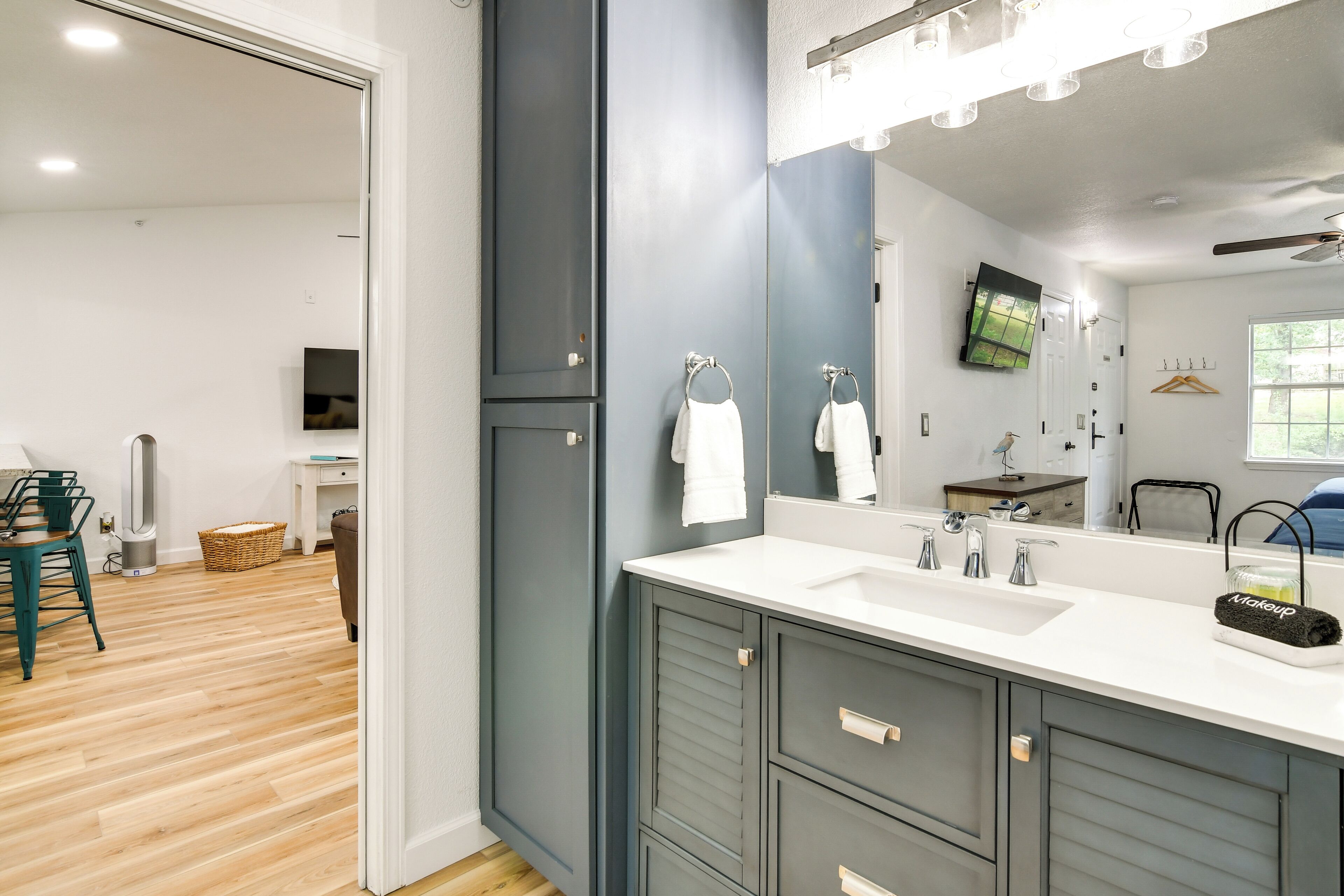 A modern bathroom with a large mirror, dual sinks, and a vanity with cabinets.