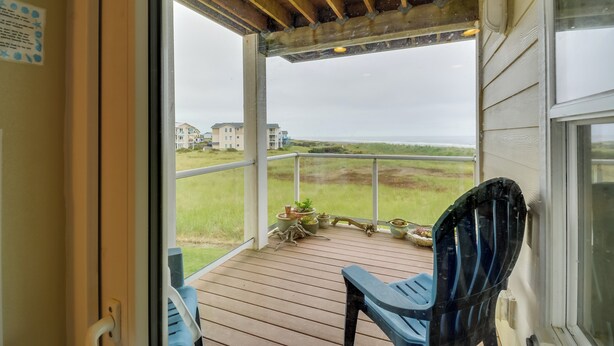 A wooden deck with a view of the ocean and houses in the distance.