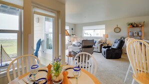 A dining area with a table set for two, a sofa, and a recliner in the background.