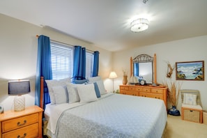 Un dormitorio ordenado con cama, mesitas de noche, cómoda y espejo.