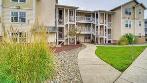 A multi-story residential building with balconies, a landscaped front yard, and a clear pathway.