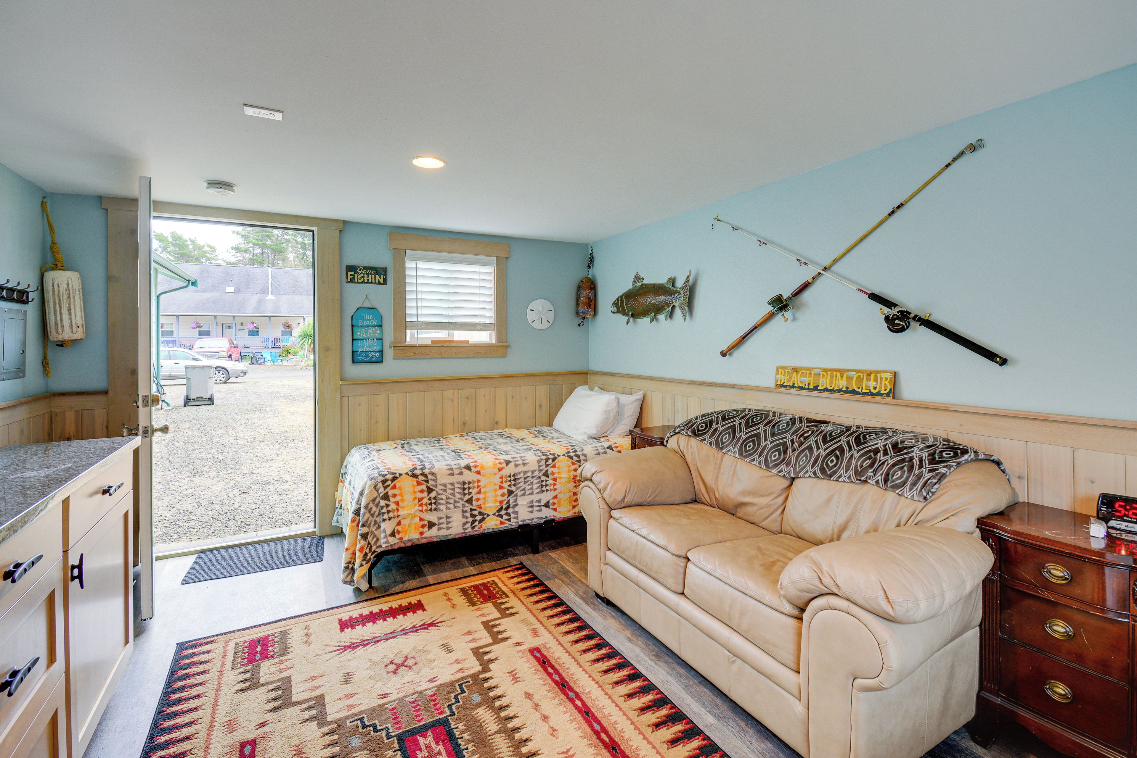 A cozy room with a bed, a couch, a wooden dresser, and fishing rods on the wall.