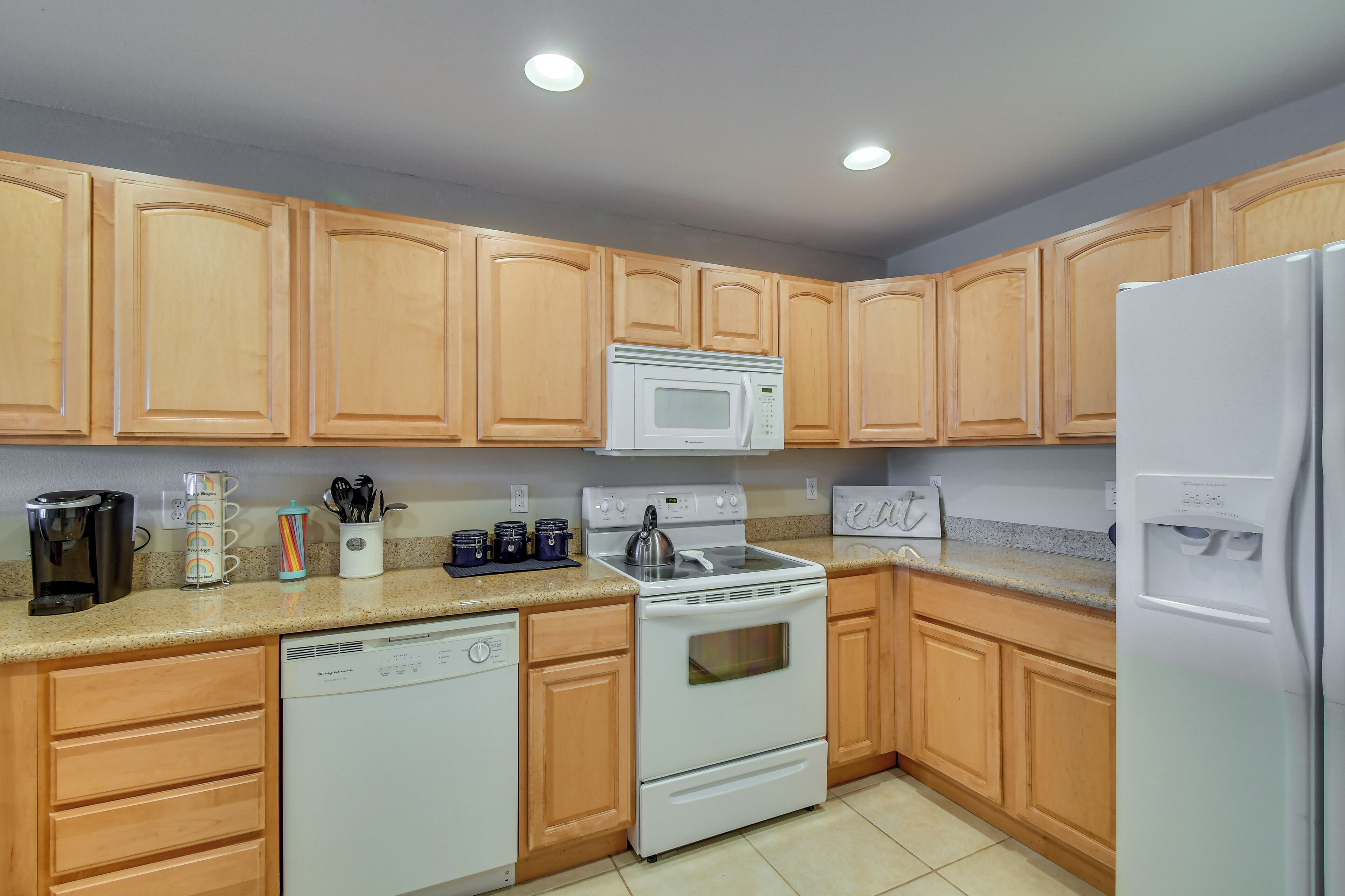A kitchen with wooden cabinets, a white stove, a microwave, a dishwasher, and a refrigerator.