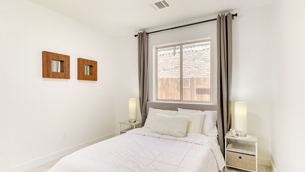 A bedroom with a large bed, two bedside tables, a window with curtains, and two wall-mounted mirrors. - Modern & Pet-friendly Austin Vacation Rental! (Austin)