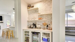 A modern kitchen with a built-in refrigerator, bar area with shelves, and stools. - Modern & Pet-friendly Austin Vacation Rental! (Austin)
