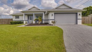 A two-story house with a garage, a well-maintained lawn, and a paved driveway. - Port Saint Lucie Vacation Rental w/ Hot Tub! (Port Saint Lucie)