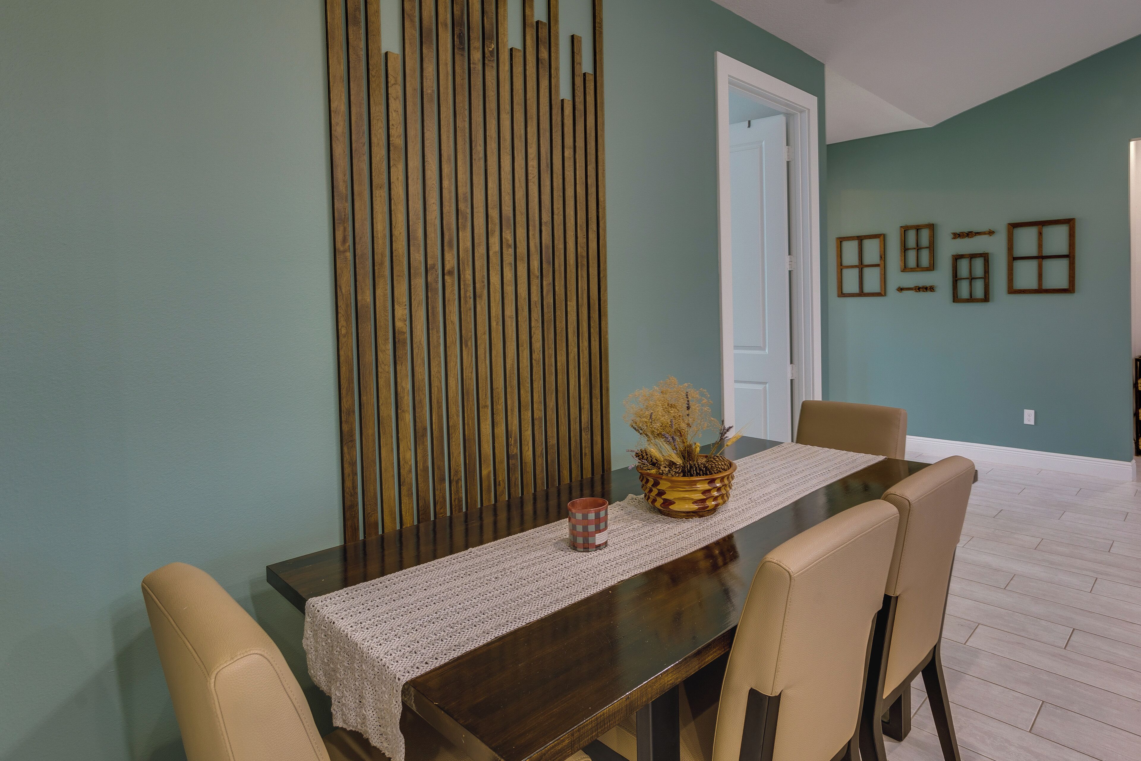 A dining area with a wooden table, beige chairs, a woven table runner, and a potted plant.