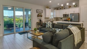 A modern living room with a sofa, coffee table, and a view through glass doors to an outdoor patio. - Port Saint Lucie Vacation Rental w/ Hot Tub! (Port Saint Lucie)