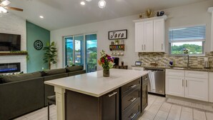 A modern kitchen with a central island, white cabinets, and a view of greenery outside. - Port Saint Lucie Vacation Rental w/ Hot Tub! (Port Saint Lucie)