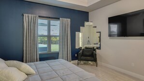 A bedroom with a bed, a chair, a mirror, and a TV. - Port Saint Lucie Vacation Rental w/ Hot Tub! (Port Saint Lucie)