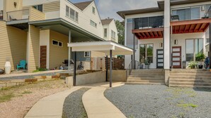 A modern residential building with a covered patio, a staircase leading to a second floor, and a small outdoor seating area. - Modern Austin Vacation Rental w/ Covered Patio (Austin)