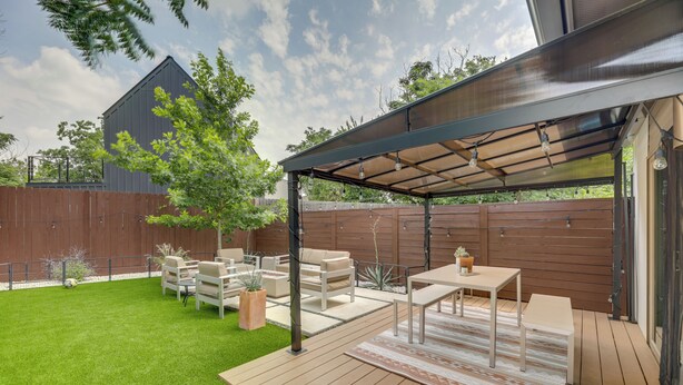 A covered patio area with outdoor furniture, a wooden deck, and a grassy lawn. - Modern Austin Vacation Rental w/ Covered Patio (Austin)