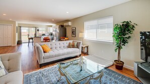 A spacious living room with a sofa, coffee table, and a potted plant.
