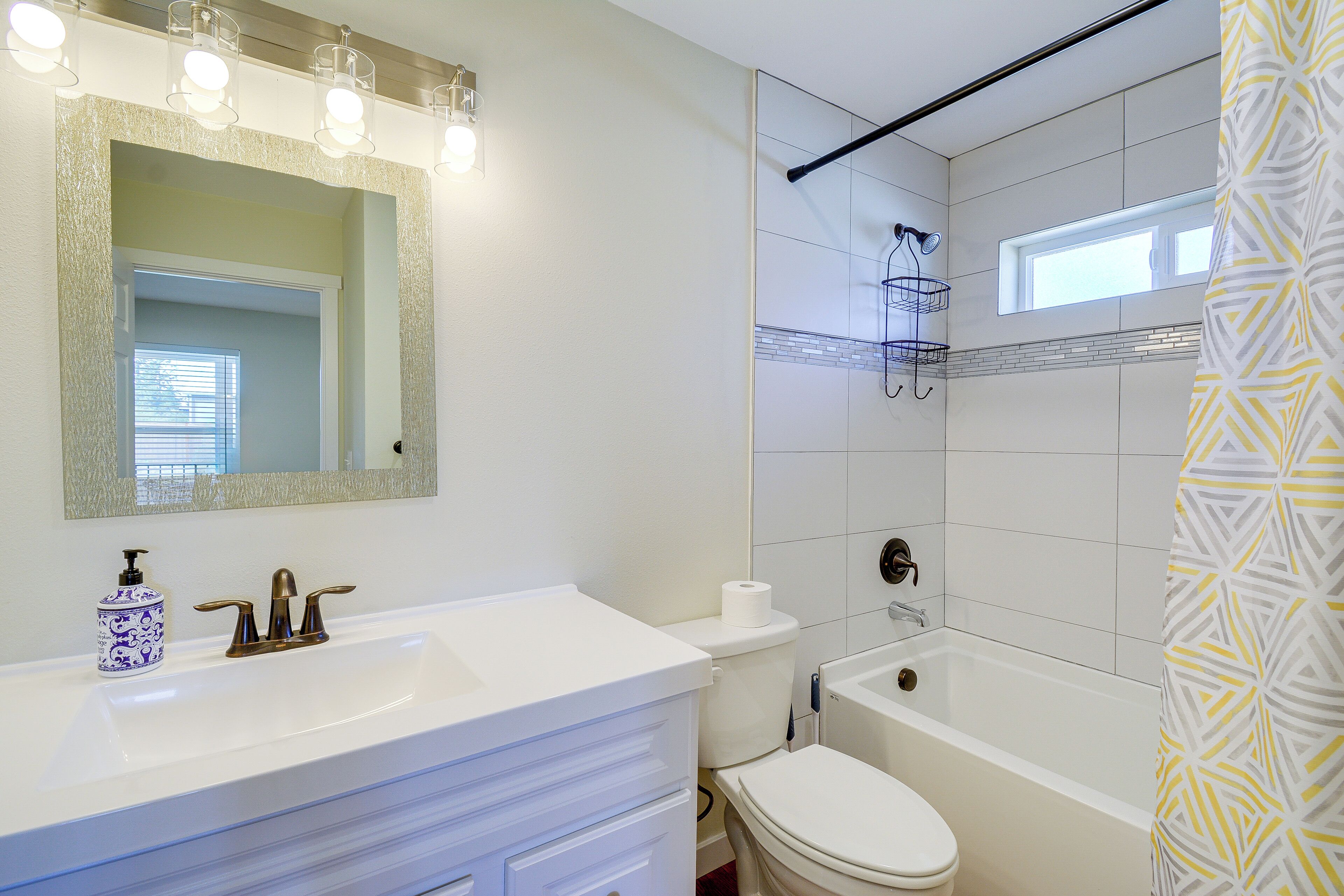 Un baño con lavamanos, tocador, inodoro y bañera blancos.