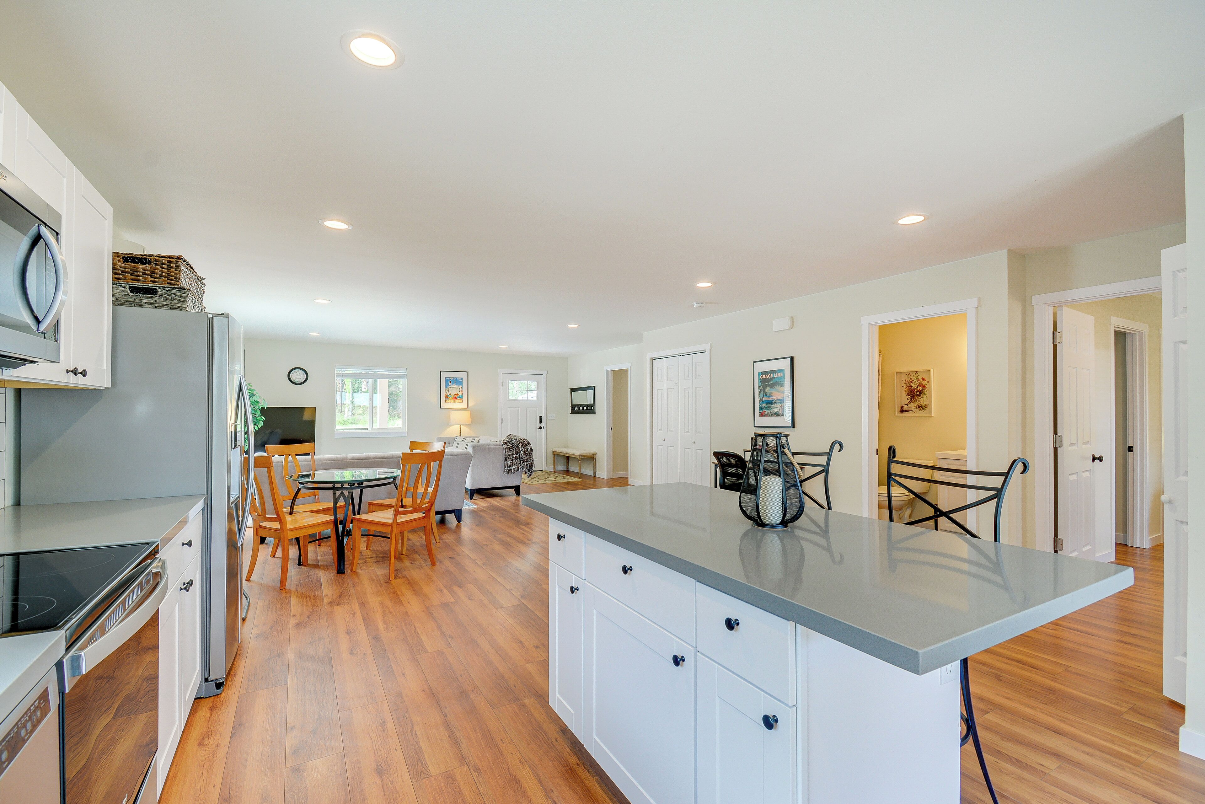 A modern kitchen with a central island, wooden flooring, and white cabinetry.