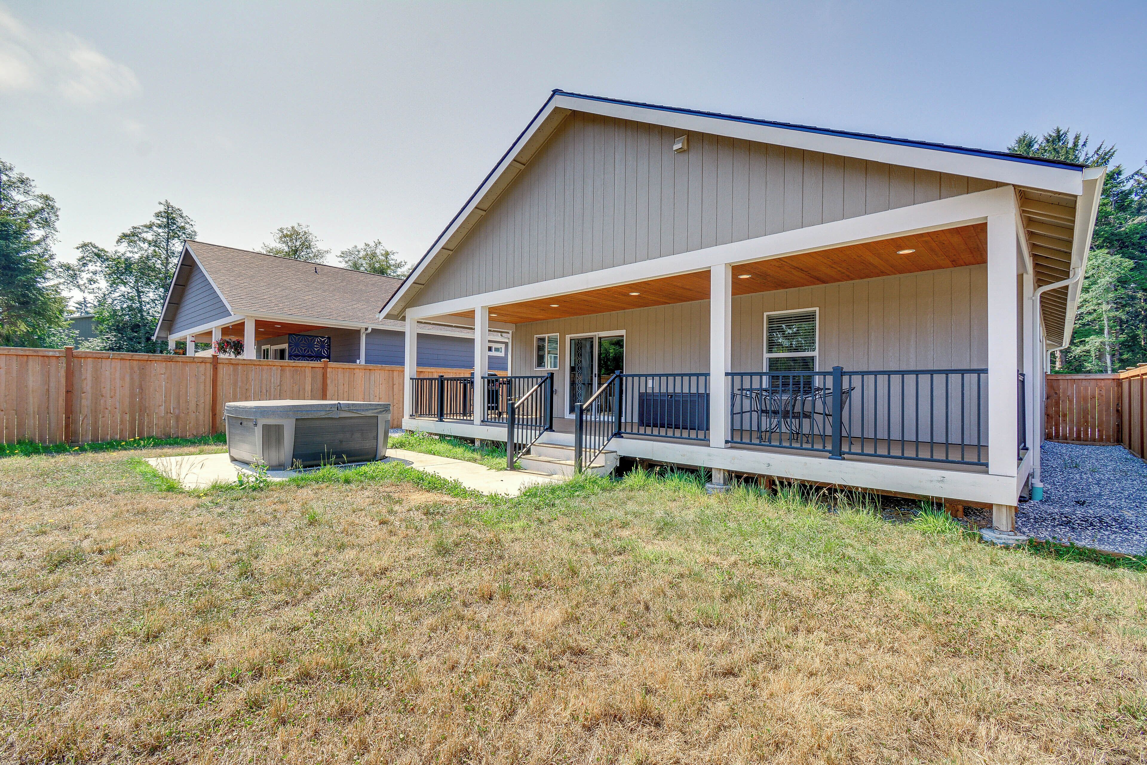 A two-story house with a covered porch and a hot tub in the backyard.