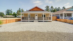 A two-story building with a wooden front porch and a gravel driveway.