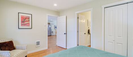 A bedroom with a bed, a chair, and a door leading to another room.