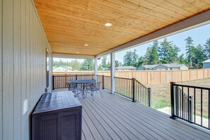 Une terrasse extérieure couverte avec un plafond en bois, une table, des chaises et un barbecue.