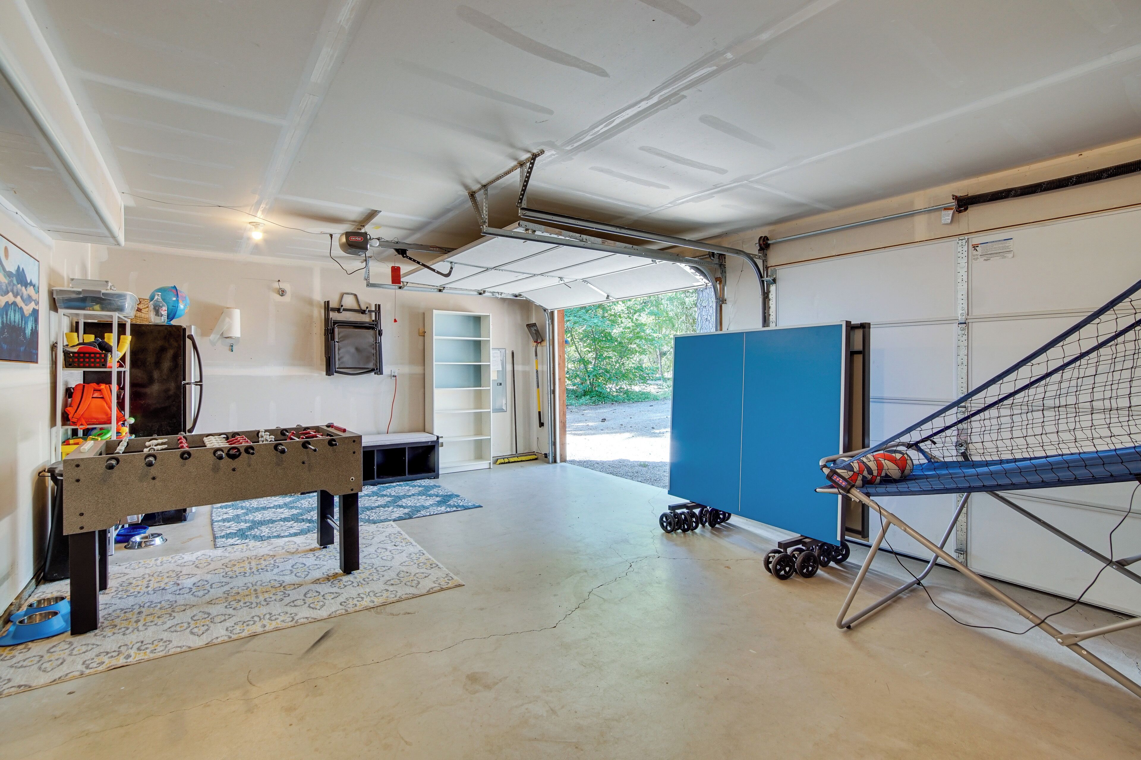 Eine Garage mit einem Kicker, einer Hängematte und einer blauen Tür.