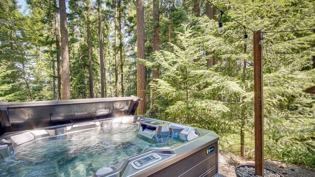 A hot tub in a forested area with a wooden deck and a stone basin. - Unwind in Cle Elum: Hot Tub & Cozy Fireplace! (Cle Elum)