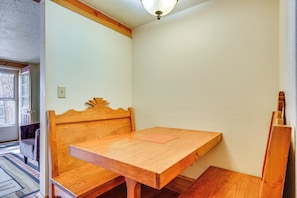 A corner room with a wooden table and bench, a door, and a light fixture. - Secluded Stonewall Cabin w/ Mountain View! (Weston)