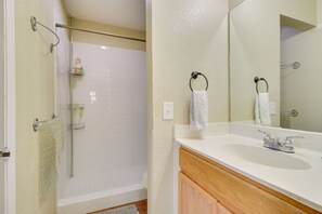 Een badkamer met een douche, een wastafel en een spiegel.