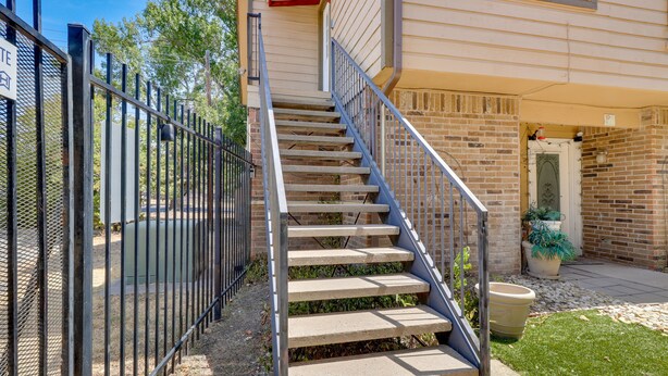 A concrete staircase with metal railings leading to a brick building entrance.
