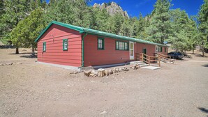 A red building with a green roof, a wooden staircase, and a rocky ground. - Colorado Cabin Near Monument Lake! (Weston)