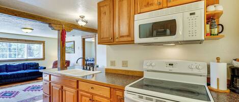 A kitchen with wooden cabinets, a white stove, and a microwave.