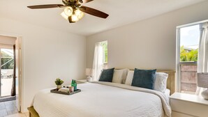 A bedroom with a large bed, a ceiling fan, a window with curtains, and a bedside table with a lamp. - Port St Lucie Oasis w/ Heated Saltwater Pool! (Port Saint Lucie)