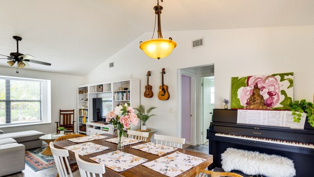 A dining area with a wooden table, white chairs, and a piano. - Port St Lucie Oasis w/ Heated Saltwater Pool! (Port Saint Lucie)