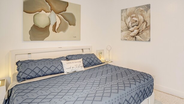 A bedroom with a bed, pillows, a nightstand, and wall art. - Upscale Treasure Coast Retreat! Port St Lucie Home (Port Saint Lucie)