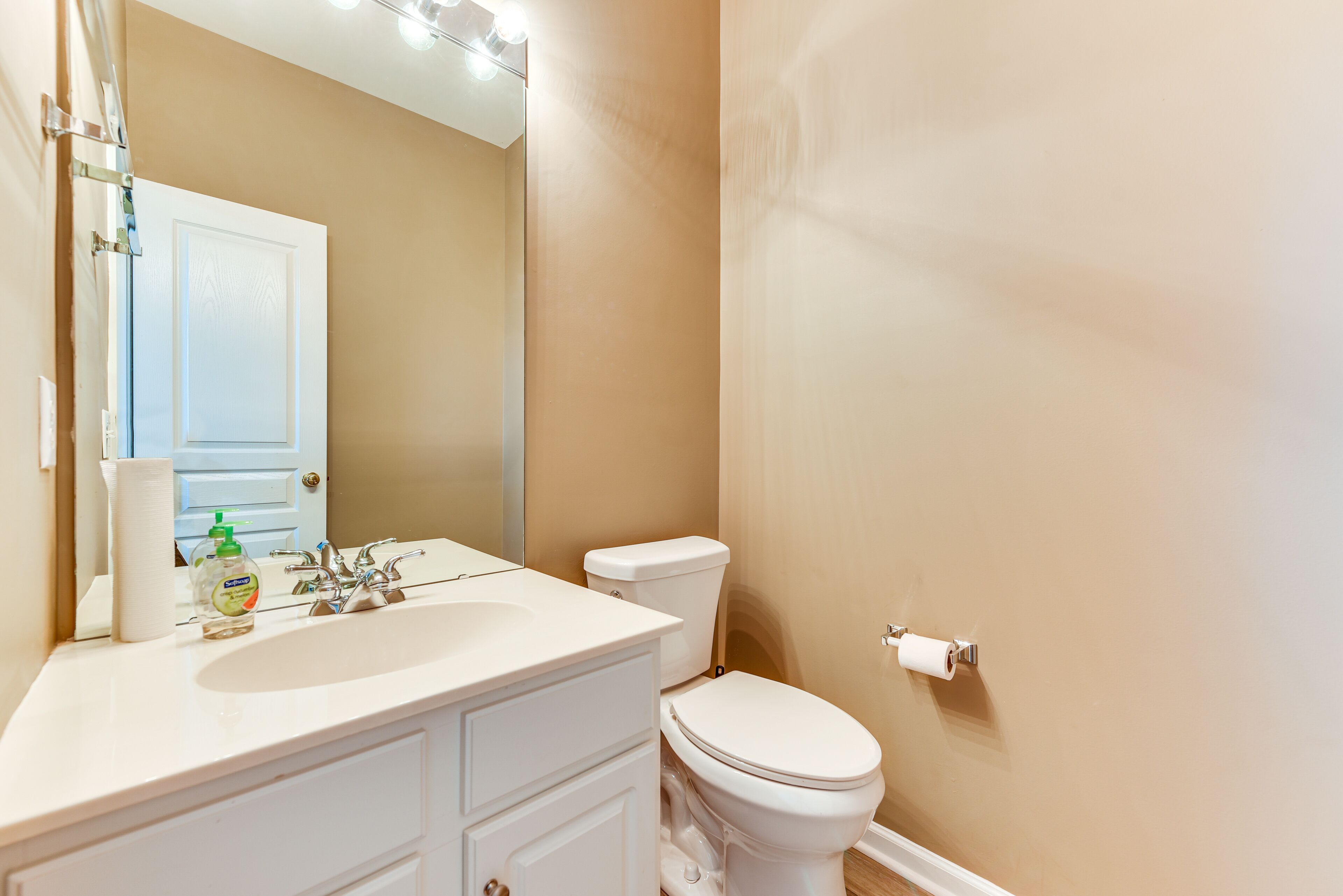A bathroom with a white sink, mirror, and toilet.