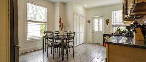A kitchen with a dining table, chairs, and a refrigerator.