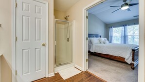 Un dormitorio con cama, ducha y ventilador de techo.