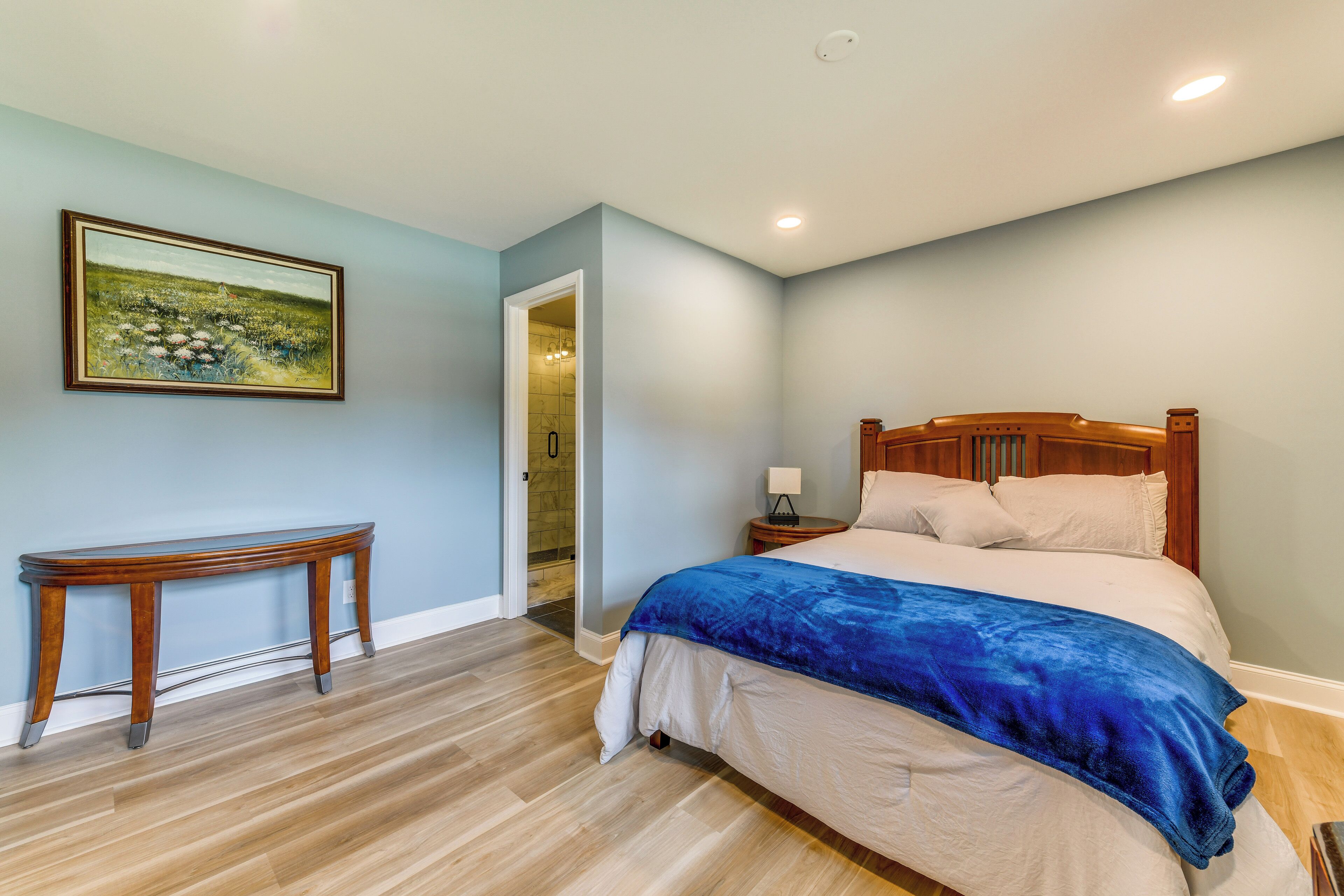 Un dormitorio con una cama de madera, una mesita de noche y un cuadro en la pared.
