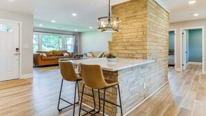 A modern kitchen with a central island, bar stools, and a hanging light fixture. - Charming Charlotte Home: 2 Mi to Downtown! (Charlotte)
