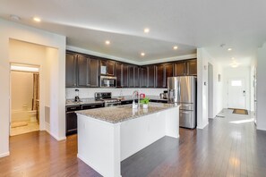A modern kitchen with dark wood cabinets, stainless steel appliances, and a large island. - Near Rocky Mountain Arsenal: Commerce City Home (Commerce City)