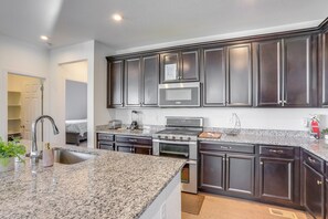 A modern kitchen with dark cabinets, granite countertops, stainless steel appliances, and a built-in microwave. - Near Rocky Mountain Arsenal: Commerce City Home (Commerce City)